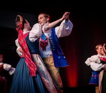 A pair of Mazowsze Ensemble performers dancing on stage in costumes from Upper Silesia
