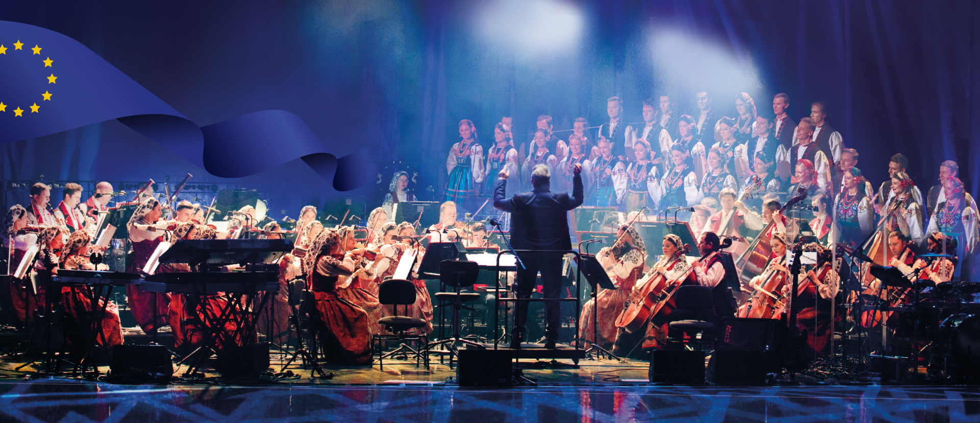The Mazowsze Ensemble Orchestra on stage in costumes from Wilanów, with conductor, Jacek Boniecki