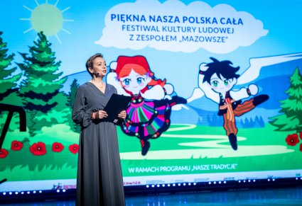 Prowadząca podczas otwarcia koncertu na scenie, w  tle grafika wydarzdenia