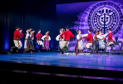 Artyści w kostiumach kurpiowskich na scenie w figurach tanecznych