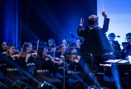 Zbliżenie na dyrygenta i orkiestrę podczas koncertu