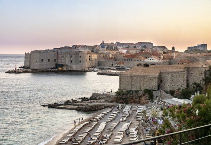 Widok na morze, plażę i budynki z piaskowca w trakcie zachodu słońca