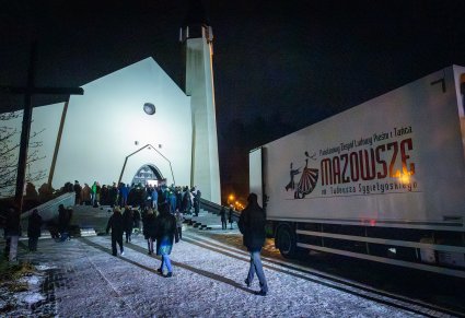 Ludzie wchodzący do kościoła, obok stojący autokar zespołu "Mazowsze"