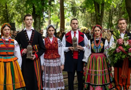 Artyści z kwiatami i zniczami na cmentarzu