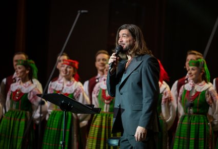 Wokalista zespołu Pectus na scenie wraz z chórem w kostiumach kurpiowskich