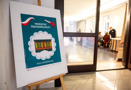 Tablica informacyjna o warsztatach rękodzielniczych przed salą