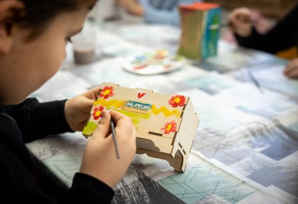 Dziecko dekorujące skrzynię wilamowską farbami podczas warsztatów