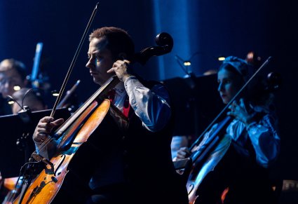 Zbliżenie na artystów orkiestry grających na instrumentach smyczkowcyh