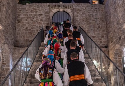 Artyści w kostiumach łowickich zmierzający do budynku po schodach