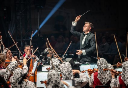 Zbliżenie na dyrygenta i orkiestrę podczas koncertu