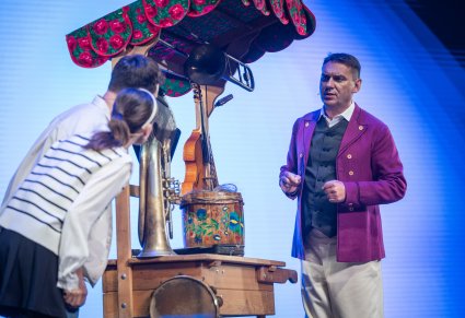 Aktorzy na scenie przy wózku z ludowymi przedmiotami