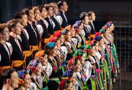 Boczny widok na Artystów Chóru w kostiumach łowickich w trakcie śpiewu