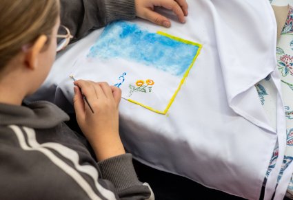 Zbliżenie na dziewczynkę dekorującą fartuszek kuchenny na warsztatach