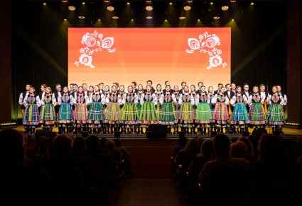 Chór w kostiumach łowickich wykonujący utwór na scenie