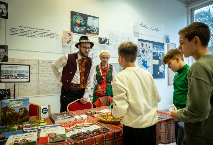 Para w strojach tradycyjnych rozmawiająca z dziećmi o wystawie