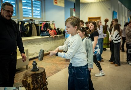 Dziecko wybijające monetę w tradycyjny sposób na wystawie