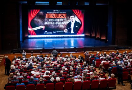 Sala widowiskowa przed koncertem z widownią i plakatem koncertowym