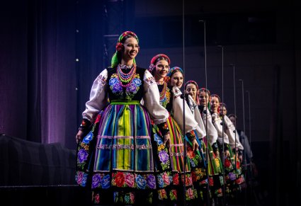 Artystki chóru w kostiumach łowickich wchodzące na scenę