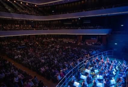 Widownia przed koncertem podczas przemówienia dyrygenta, widoczna orkiestra