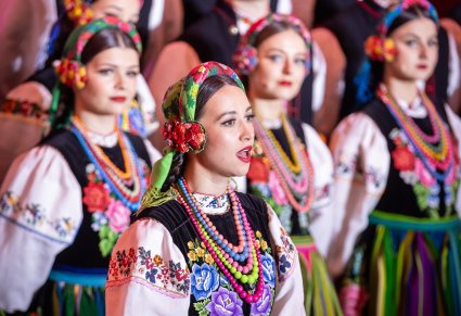 Zbliżenie na solistkę chóru podczas koncertu z widocznych chórem w tle