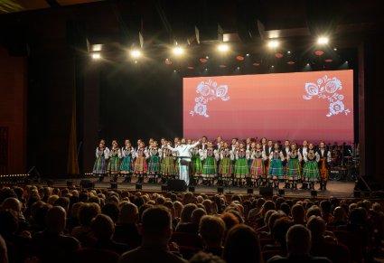 Wokalista zespołu Pectus na scenie wraz z chórem w kostiumach łowickich