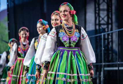 Zbliżenie na chórzystki w kostiumach łowickich, wchodzące na scenę