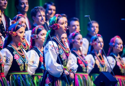 Zbliżenie na solistkę chóru podczas koncertu z widocznych chórem w tle