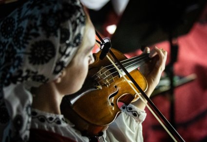 Zbliżenie na artystkę orkiestry grającą na skrzypcach