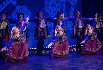 Tancerki w kostiumach podegrodzkich kłaniające się na scenie, w tle widoczni tancerze