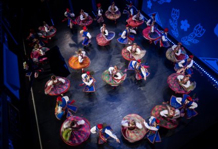 Kadr z góry na scenę, grupa tancerzy w kostiumach krakowskich podczas występu