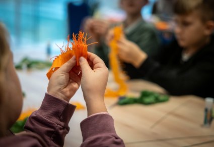 Zbliżenie na dziewczynkę robiącą kwiatka z bibuły podczas warsztatów