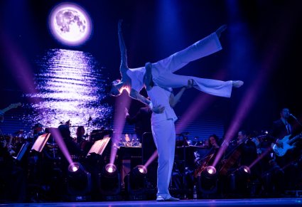 Para taneczna w figurze tanecznej na scenie, w tle widoczna orkiestra