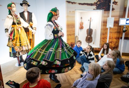 Zwiedzający ekspozycję w Centrum Folkloru Polskiego "Karolin" z oprowadzającą w kostiumie łowickim