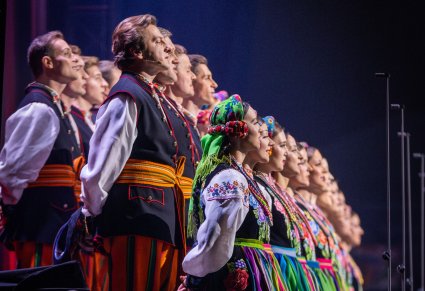 Zbliżenie od boku na chór w kostiumach łowickich podczas koncertu na scenie