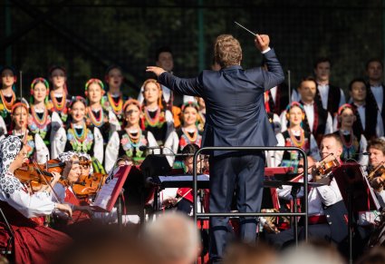 Dyrektor zespołu, dyrygujący podczas koncertu, w tle chór