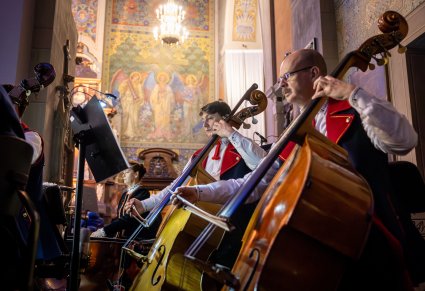 Zbliżenie na artystów orkiestry grających na kontrabasach