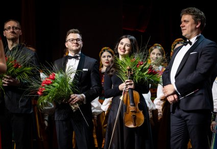 Dyrygenci i koncertmistrzyni z kwiatami na scenie