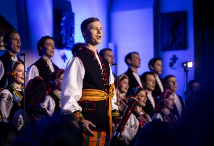 Solista chóru podczas występu na koncercie, w tle widoczny chór