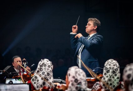 Zbliżenie na dyrygenta podczas koncertu, widoczna orkiestra