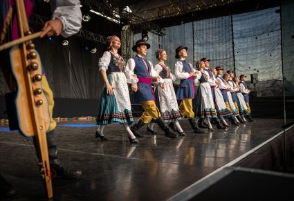 Tancerze w kostiumach kaszubskich podczas występu, widoczne diabelskie skrzypce