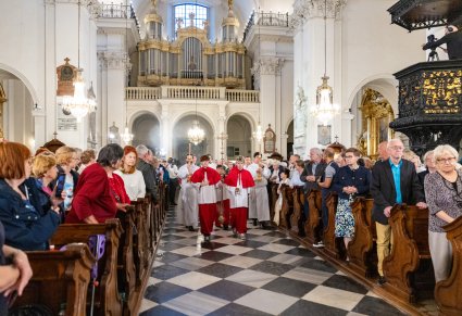 Zebrani wierni w ławach, po Alejce zmierzający duchowni wraz z ministrantami, w tle widoczne pokaźne organy kościelne