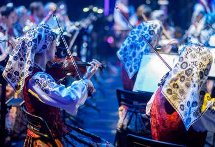 Zbliżenie na artystki orkiestry grające na skrzypcach