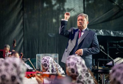Dyrygent- Dyrektor zespołu "Mazowsze" zwrócony w stronę Orkiestry, w kostiumach wilanowskich