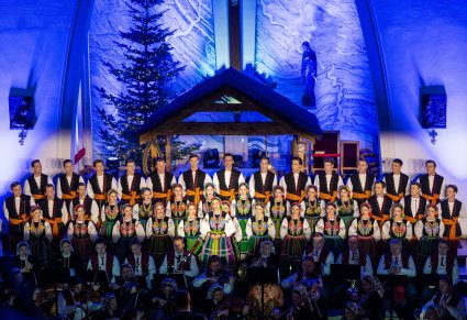 Solistka chóru podczas występu na koncercie, w tle widoczny chór