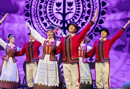 Grupa tancerzy w kostiumach kurpiowskich na scenie