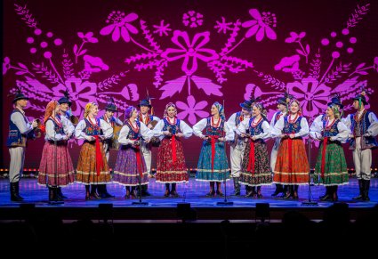 Grupa taneczna w kostiumach limanowskich na scenie w trakcie śpiewu