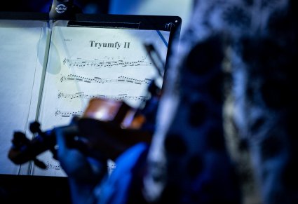 Zbliżenie na nuty i artystkę grającą na skrzypcach