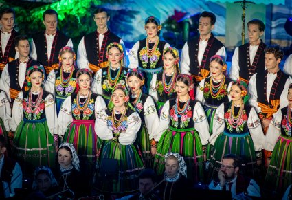 Zbliżenie na solistkę chóru podczas koncertu z widocznych chórem w tle