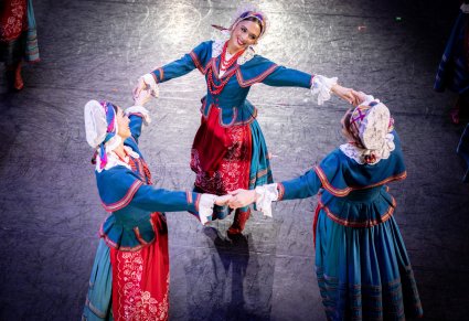 Zbliżenie na 3 Artystki w kostiumach kujawskich w trakcie wykonywania choreografii tanecznej