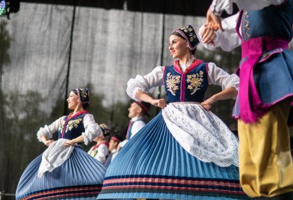 Trzy pary Artystów w kostiumach kaszubskich na scenie wykonujący choreografię taneczną